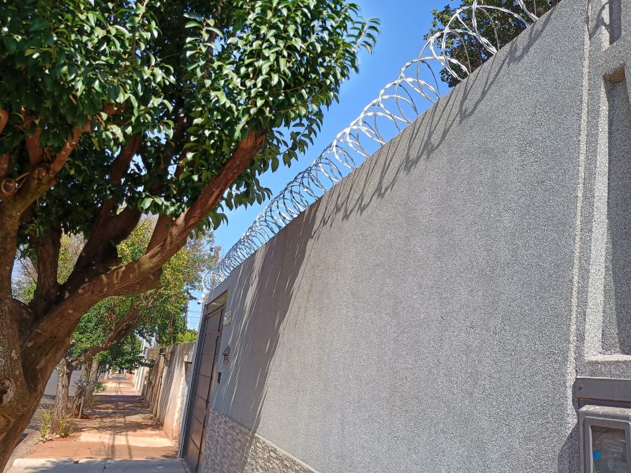 Concertina instalada em muro cinza na calçada